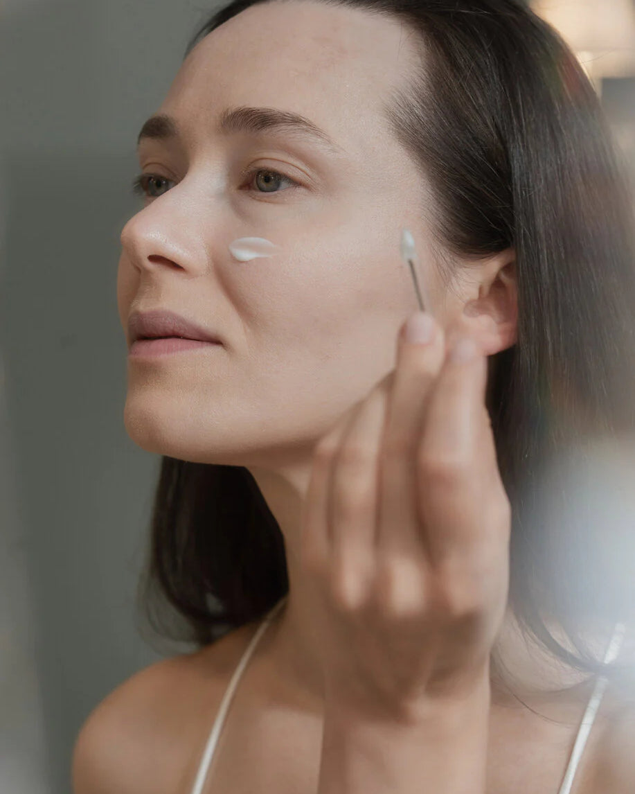 Une femme en train d'appliquer un produit sur son visage