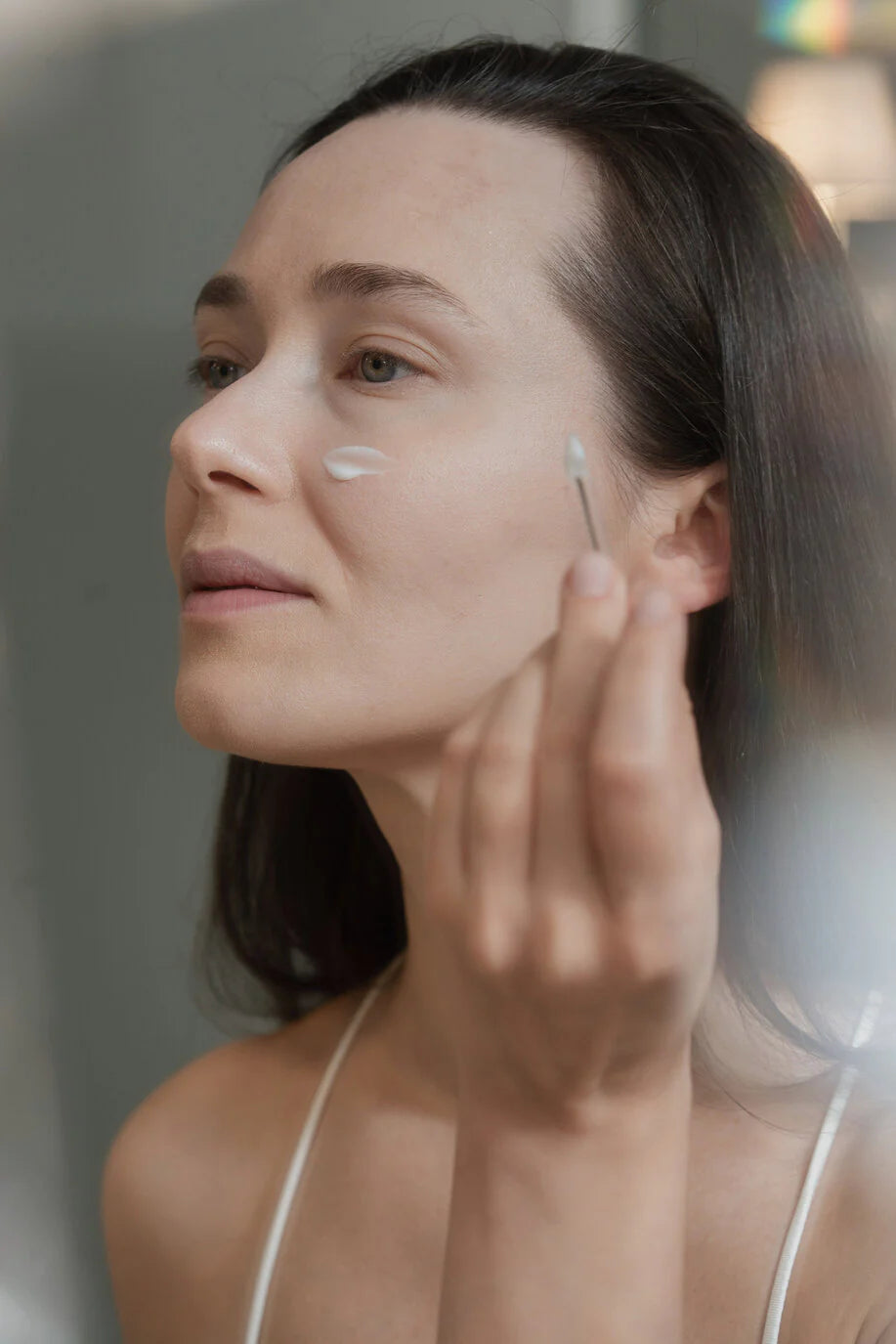 Une femme en train d'appliquer un produit sur son visage