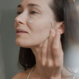 Une femme en train d'appliquer un produit sur son visage