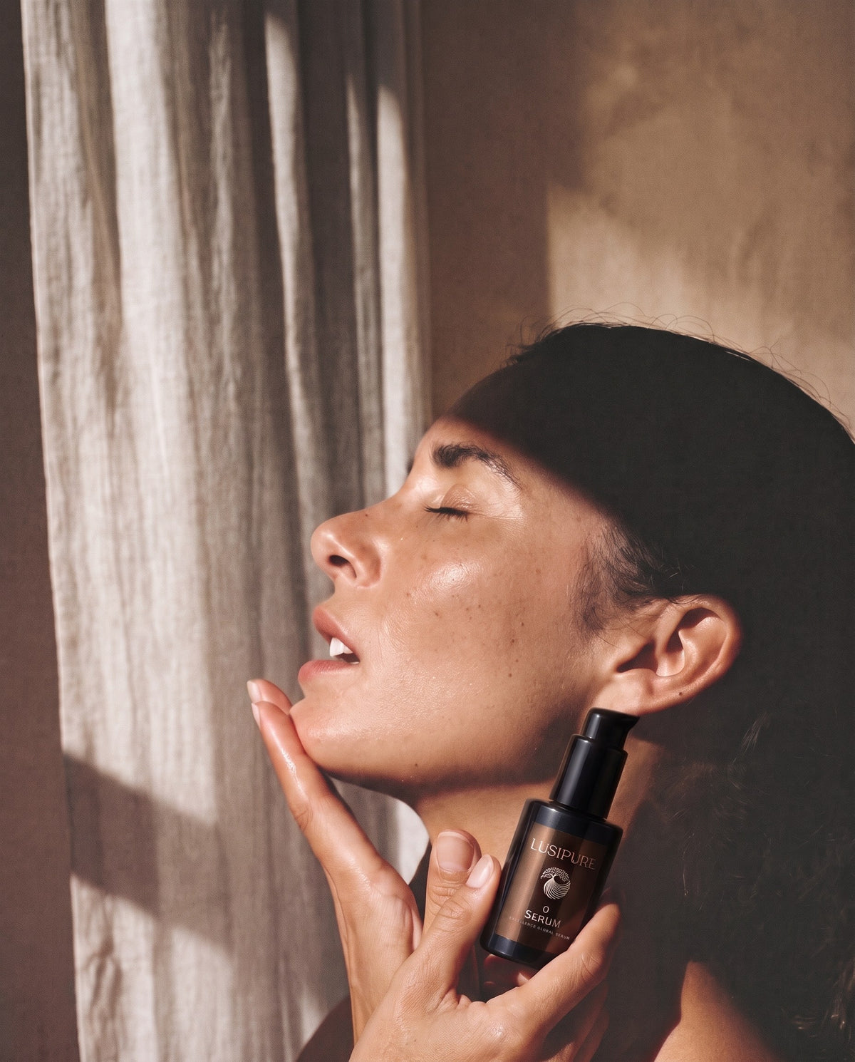 Woman applying Lusipure O Serum to her neck in warm sunlight